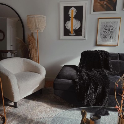 Alanna Martine's living room featuring a white chair, a dark gray sofa with a black furry throw, and a glass coffee table.