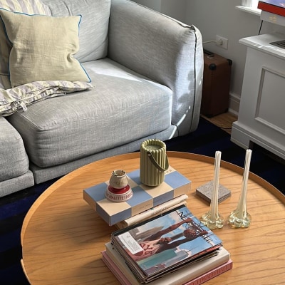 Elizabeth Anne Venter's living room featuring secondhand furniture, including a gray sofa and a round wooden coffee table.